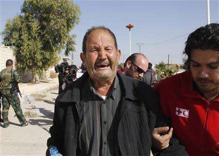 A volunteer from the Syrian Arab Red Crescent helps a weeping man as Syrian families leave the besieged town of al-Moadamiyeh, which is controlled by opposition fighters, in Damascus countryside October 29, 2013. REUTERS/Khaled al-Hariri