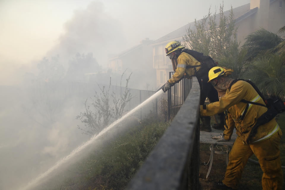 Firefighters make a stand on an advancing wildfire from the backyard of a home Friday, Oct. 11, 2019, in Porter Ranch, Calif. (AP Photo/Marcio Jose Sanchez)