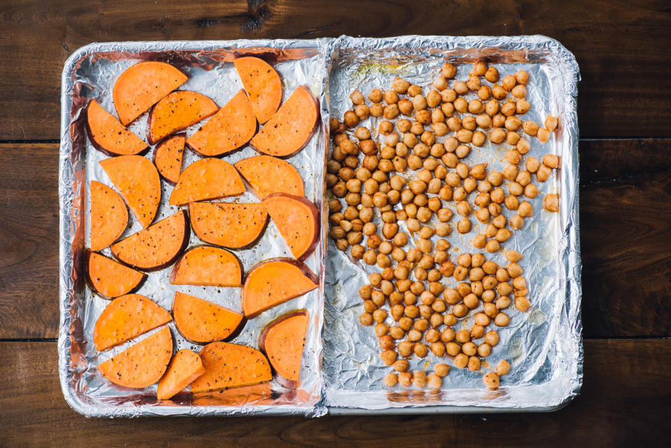 A sheet pan with aluminum foil topped with sweet potatoes and chickpeas.