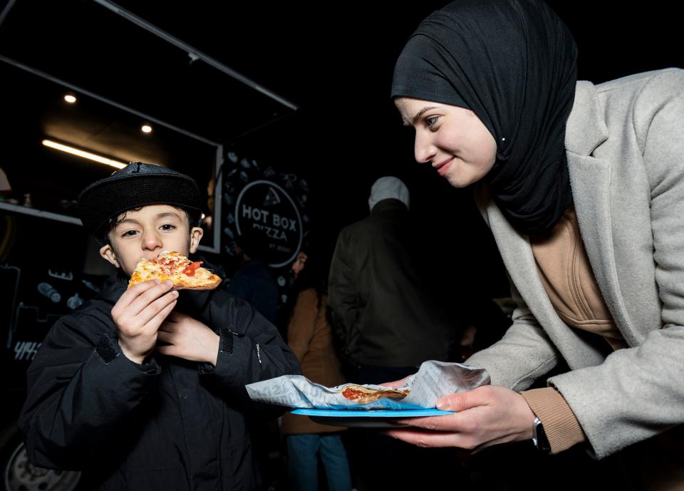 Rawan Sarsour of Milwaukee brings her son 6-year-old Eskandar Saed, who is fasting for the first time, a slice of pizza from Hot Box Pizza at the Suhoor Food Truck Festival, which took place at night to accommodate for Muslims who are fasting for Ramadan Friday at the Islamic Society of Milwaukee.