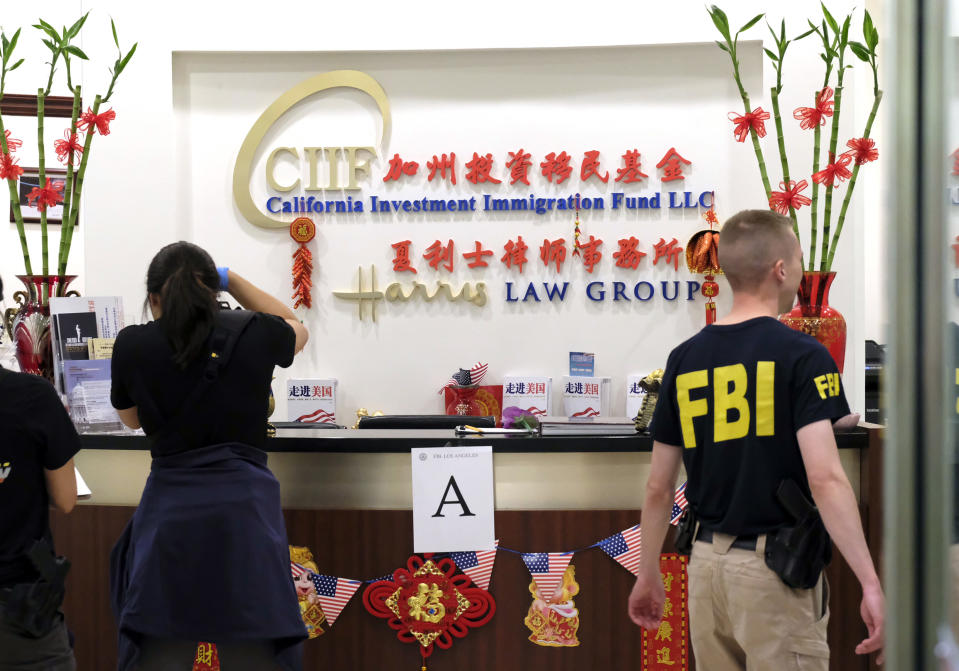 Federal agents are seen inside California Investment Immigration Fund in San Gabriel, Calif., Wednesday, April 5, 2017. Federal authorities on Wednesday raided the Los Angeles-area business they say cheated a U.S. government visa program to obtain green cards for wealthy Chinese investors. (AP Photo/Rich Vogel