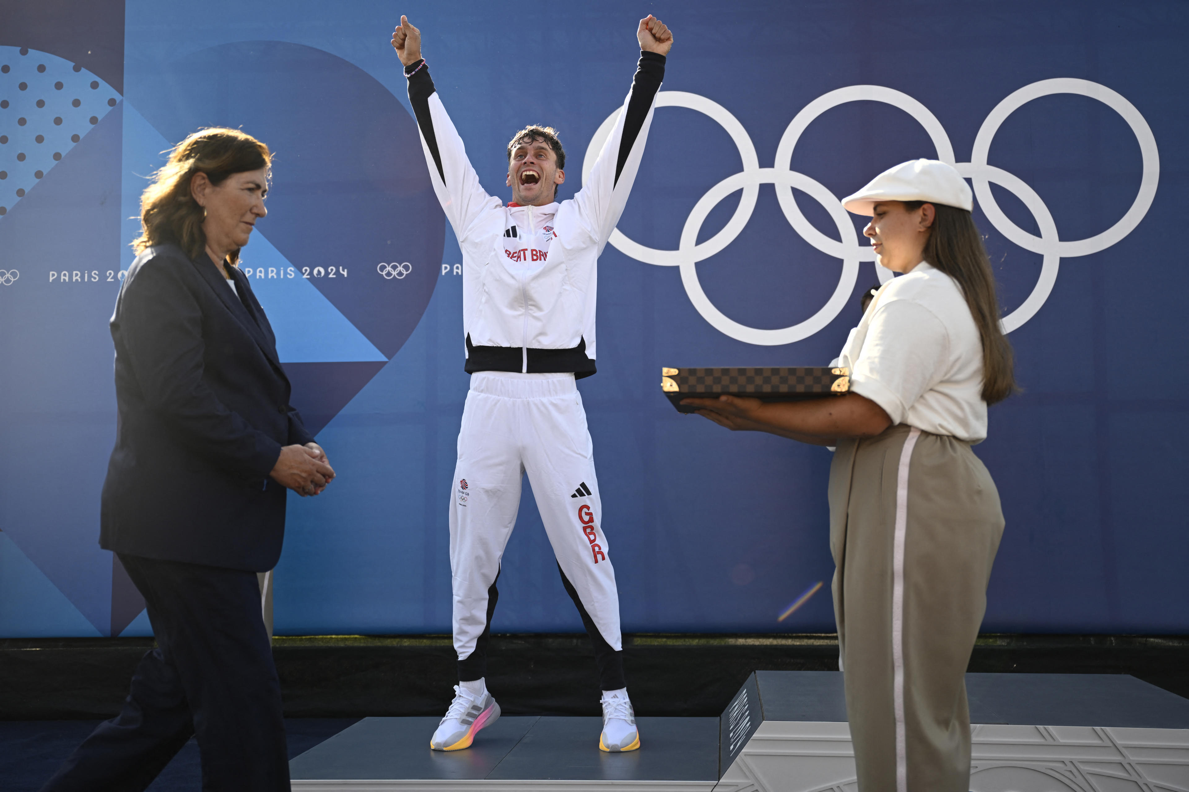 Silver medallist Britain's Adam Burgess (C) celebrates on the posium during the medal ceremony after the men's canoe single final of the canoe slalom competition at Vaires-sur-Marne Nautical Stadium in Vaires-sur-Marne during the Paris 2024 Olympic Games on July 29, 2024. (Photo by Olivier MORIN / AFP)