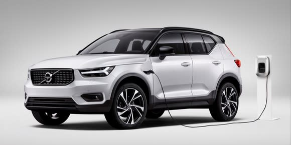 A white Volvo XC40 plug-in hybrid SUV, shown plugged into a charger.