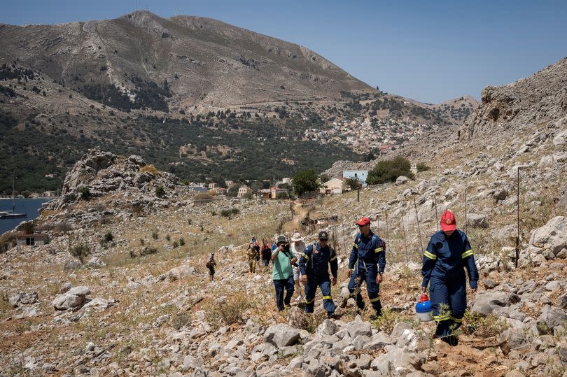 Firefighters take part in a search and rescue operation for a missing British journalist in the island of Symi