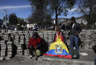 Volunteers take a break from stacking paving stones during a cleanup effort in the aftermath of violent protests against the government, in Quito, Ecuador, Monday, Oct. 14, 2019. Ecuador celebrated a deal President Lenín Moreno and indigenous leaders struck late Sunday to cancel a disputed austerity package and end nearly two weeks of protests that have paralyzed the economy and left seven dead. (AP Photo/Fernando Vergara)