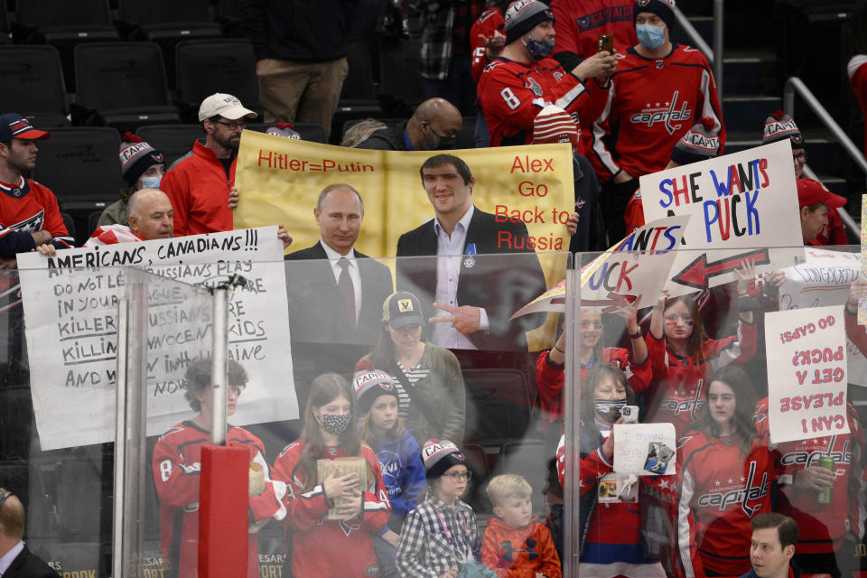 A sign is held up showing Vladimir Putin and Washington Capitals' Alex Ovechkin during warmups before an NHL hockey game between the Capitals and the Seattle Kraken, Saturday, March 5, 2022, in Washington. (AP Photo/Nick Wass)