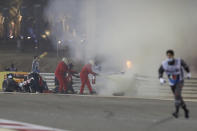 Staff extinguish flames from Haas driver Romain Grosjean of France's car after a crash during the Formula One race in Bahrain International Circuit in Sakhir, Bahrain, Sunday, Nov. 29, 2020. (Tolga Bozoglu, Pool via AP)