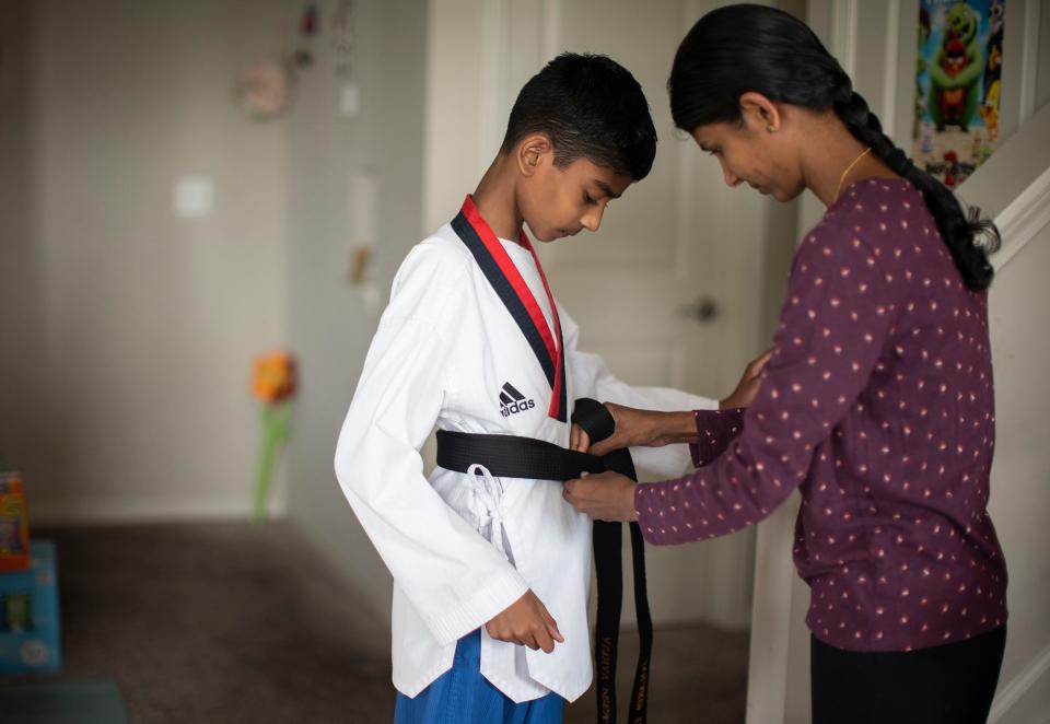 Priya Darshini Jegadeesan helps her son, Avinav Prem Anand, with his taekwondo uniform. The 11-year-old, who has dozens of medals in martial arts, will be competing in the Scripps National Spelling Bee for the first time.