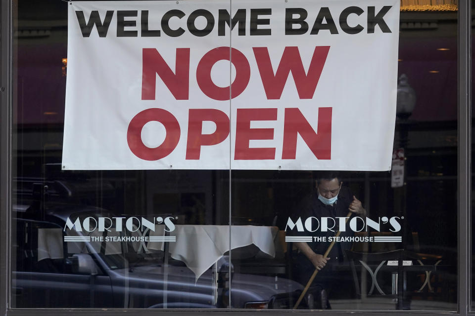 FILE - In this March 4, 2021, file photo, a sign reading "Welcome Back Now Open" is posted on the window of a Morton's Steakhouse restaurant as a man works inside in San Francisco. The Institute for Supply Management, an association of purchasing managers, reported Monday, April 5 that the U.S. services sector, which employs most Americans, recorded record growth in March as orders, hiring and prices all surged. (AP Photo/Jeff Chiu, File)