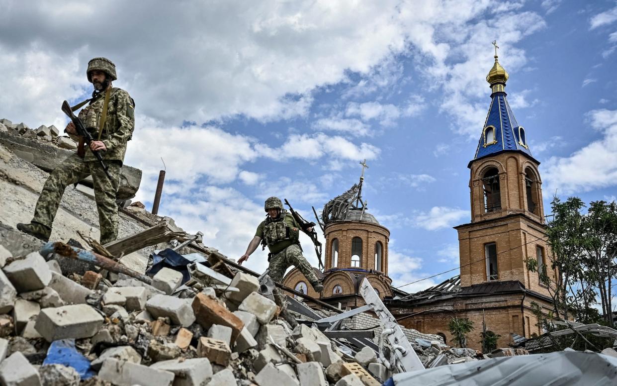 Ukrainian servicemen patrol an area heavily damaged by Russian military strikes