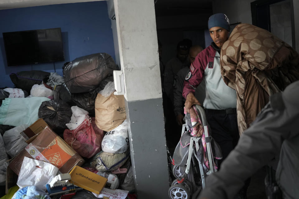 A road paramedic from the Transportation Ministry, better known as Road Angels, carries a baby carrier to a truck loaded with clothes and other donated materials collected in the capital for those affected by flooding and a massive landslide, in Caracas, Venezuela, Tuesday, Oct. 11, 2022. A landslide on Saturday night killed dozens in the town of Las Tejerías and left many homeless. (AP Photo/Matias Delacroix)