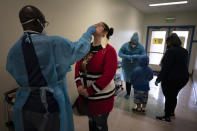 School employee Amanda Anguiano gets tested for COVID-19 on the first day of in-person learning at Maurice Sendak Elementary School in Los Angeles, Tuesday, April 13, 2021. More than a year after the pandemic forced all of California's schools to close classroom doors, some of the state's largest school districts are slowly beginning to reopen this week for in-person instruction. (AP Photo/Jae C. Hong)