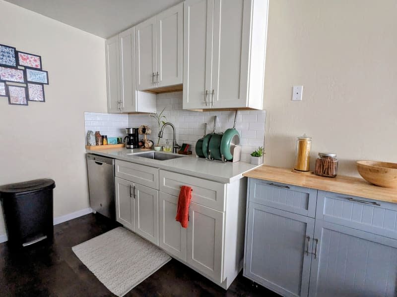 Off white/beige kitchen with white cabinets and dark brown floor