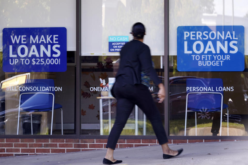 FILE - In this Oct. 1, 2020, file photo, a woman walks past a personal finance loan office in Franklin, Tenn. President-elect Joe Biden will inherit a mangled U.S. economy, one that never fully healed from the coronavirus and could suffer again as new infections are climbing. The once robust recovery has shown signs of gasping after federal aid lapsed. Ten million remain jobless and more layoffs are becoming permanent. The Federal Reserve found that factory output dropped. (AP Photo/Mark Humphrey, File)