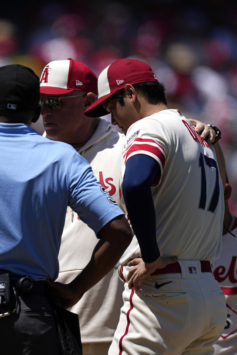 Los Angeles Angels manager Phil Nevin, center, talks with starting pitcher Shohei Ohtani before taking him out of the game due to arm fatigue during the second inning in the first baseball game of a doubleheader Wednesday, Aug. 23, 2023, in Anaheim, Calif. (AP Photo/Mark J. Terrill)