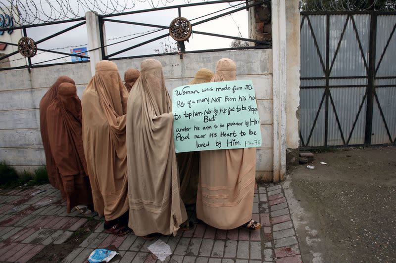 Women supporters of the political and religious party Jamiat Ulema-e-Islam-Fazal (JUI-F) clad in burkas, hold a placard as the head to attend an Aurat March, or Women's March, in Peshawar