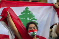 An anti-government protester shouts slogans while wearing a mask with the colors of the Lebanese flag in Beirut, Lebanon, Thursday, July 2, 2020. Major retailers in Lebanon announced Thursday they will temporarily close in the face of an increasingly volatile currency market and their inability to set prices while the local currency tumbles before the dollar. (AP Photo/Hassan Ammar)