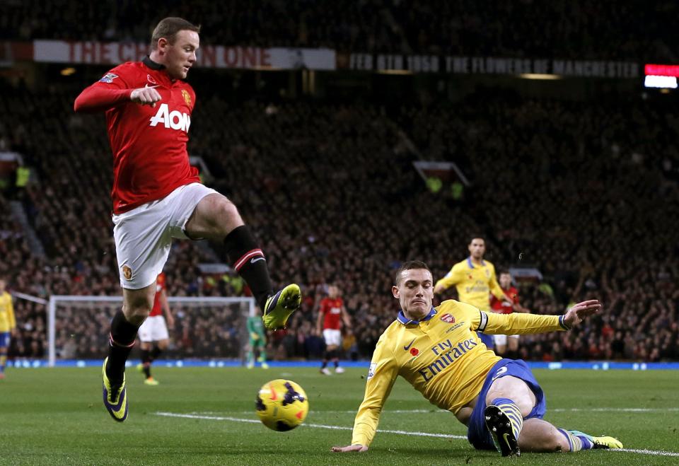 Arsenal's Thomas Vermaelen challenges Manchester United's Wayne Rooney (L) during their English Premier League soccer match at Old Trafford in Manchester, northern England, November 10, 2013.