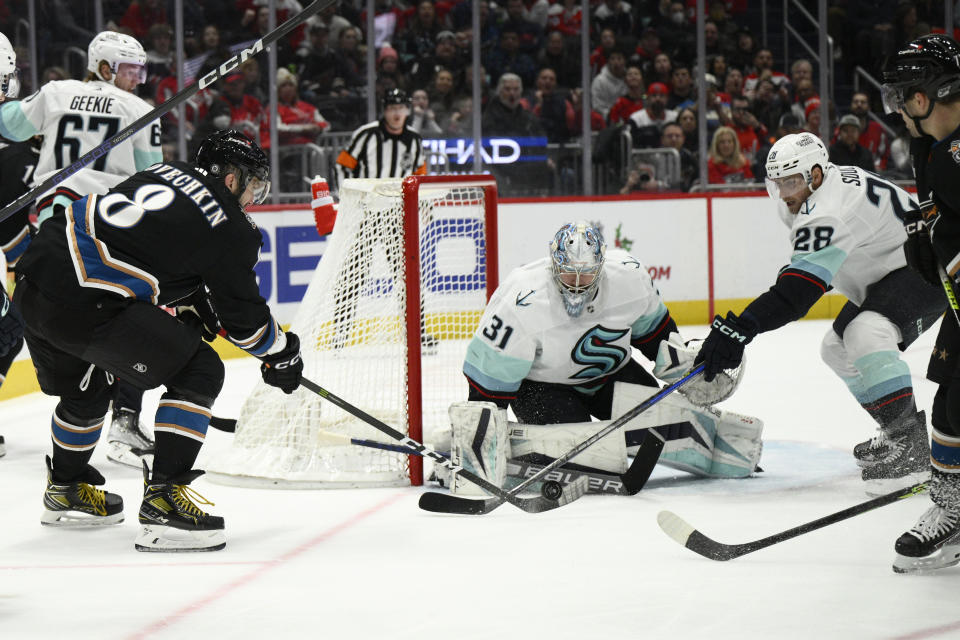 Washington Capitals left wing Alex Ovechkin (8) tries to get the puck past Seattle Kraken goaltender Philipp Grubauer (31) and defenseman Carson Soucy (28) during the first period of an NHL hockey game Friday, Dec. 9, 2022, in Washington. (AP Photo/Nick Wass)