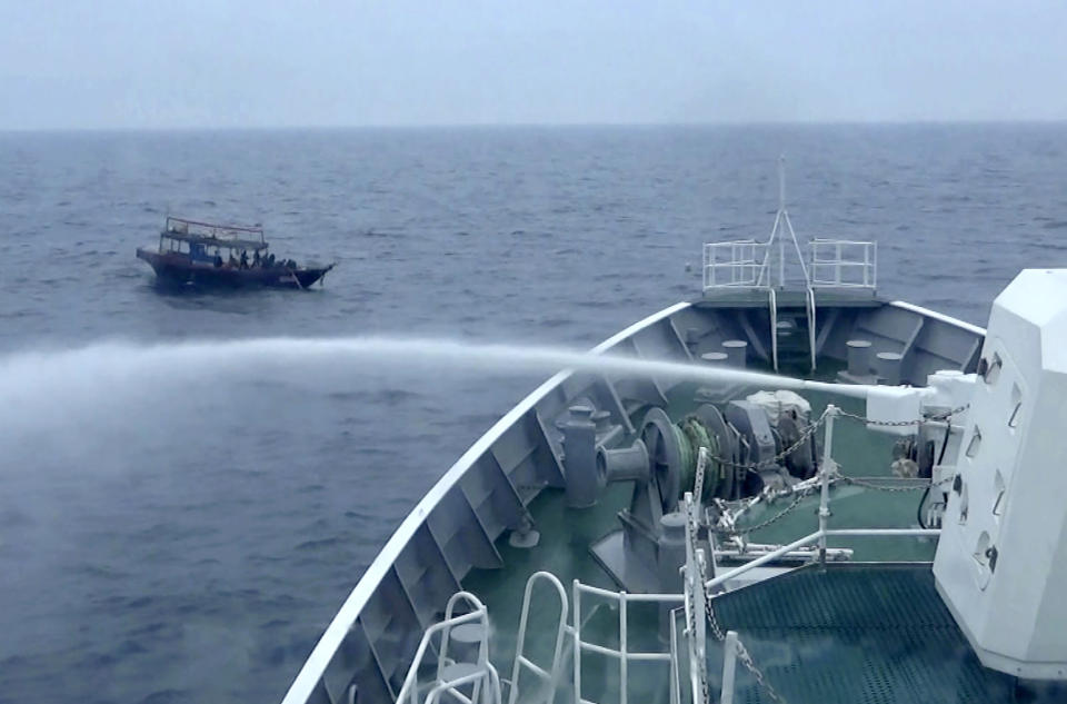 In this late May, 2019, image from video provided by Japan Coast Guard, Japan Coast Guard patrol boat sprays water to a North Korean fishing boat after the fishing boat didn't ignore the warning to evacuate in the waters near Yamatotai, Japan. Japanese Coast Guard says its patrol boats have been pushing back hundreds of North Korean poachers swarming toward fishing grounds off Japan’s northern coast.(Japan Coast Guard via AP)