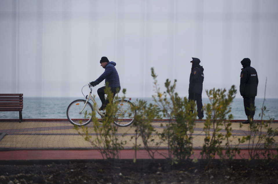 In a photo taken through a fence, security personnel patrol a boardwalk outside the Olympic Park as security measures are put into place ahead of the 2014 Winter Olympics, Wednesday, Jan. 29, 2014, in Sochi, Russia. (AP Photo/Pavel Golovkin)