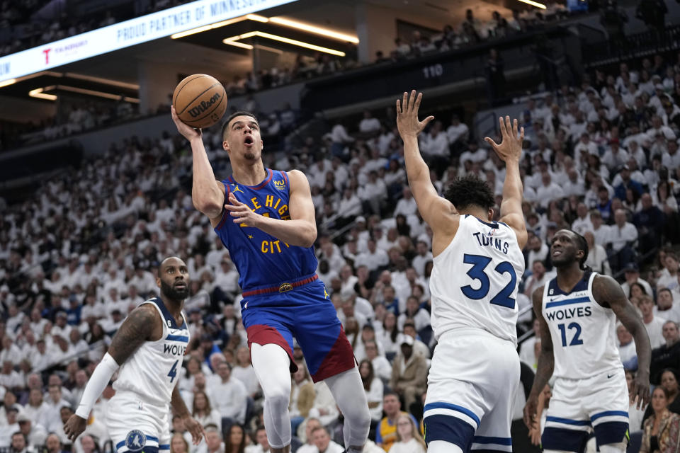 Denver Nuggets forward Michael Porter Jr., left, shoots against Minnesota Timberwolves center Karl-Anthony Towns (32) during the first half of Game 3 of an NBA basketball first-round playoff series Friday, April 21, 2023, in Minneapolis. (AP Photo/Abbie Parr)