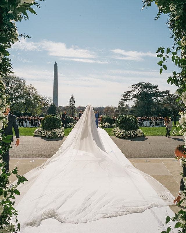 Naomi Biden's wedding dress train billows behind her as she walks down the aisle.