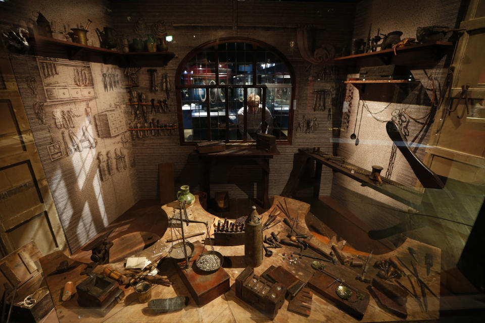 In this Monday, Oct. 7, 2013 photo, a museum employee, poses by the window of a recreation of a jeweller's workshop based on an engraving by French goldsmith Etienne Delaunne in around 1576, on display in the exhibition 'The Cheapside Hoard: London's Lost Jewels' at the Museum of London in the City of London. Diamonds may be forever, but a lot of jewelry doesn’t survive through the centuries. Rings and bracelets get broken up for re-use, pearls decay, gold is melted down. That explains the excitement over a new London exhibition of the Cheapside Hoard _ a trove of almost 500 gemstones and pieces of jewelry from the 16th and 17th centuries, dug up by workmen demolishing a building in London more than 100 years ago.(AP Photo/Sang Tan)