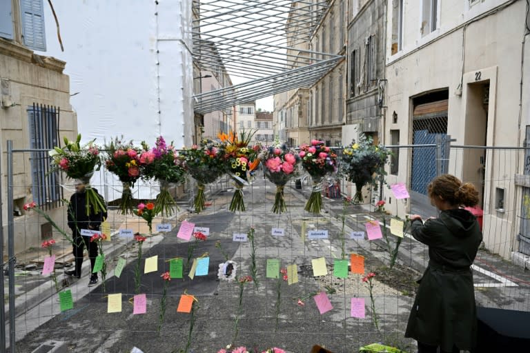 Une femme laisse un message lors d'une cérémonie commémorative marquant le premier anniversaire de l'effondrement d'un immeuble dans la rue Tivoli à Marseille, le 9 avril 2024 (Nicolas TUCAT)