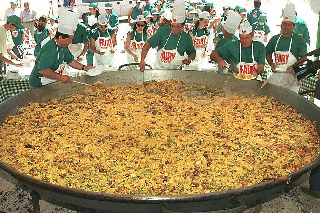 Spanish chefs serve a giant paella from one of seven enormous pans for about 15,000 people in Madrid 13 June at a benefit for UNICEF.