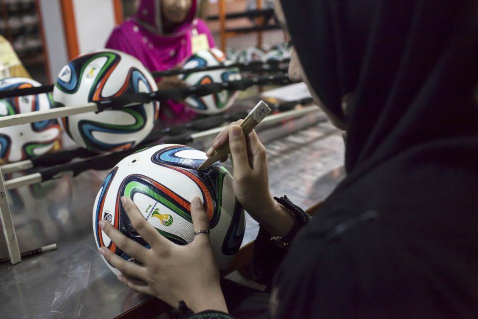 An employee conducts the final check on a ball inside the soccer ball factory that produces official match balls for the 2014 World Cup in Brazil, in Sialkot, Punjab province