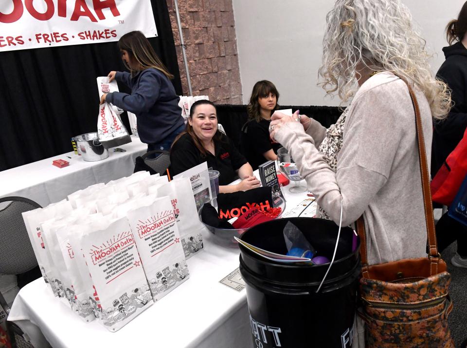 Jill Trout (center) speaks to a visitor to the Mooyha Burgers, Fries & Shakes booth.