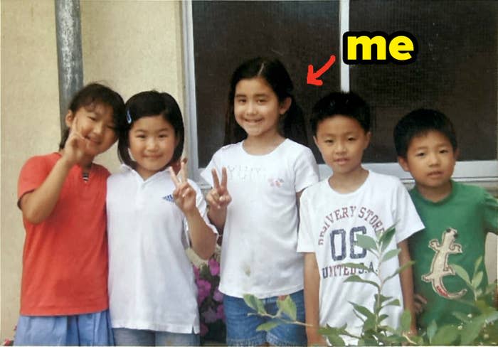 Five children smiling and posing together, two making peace signs