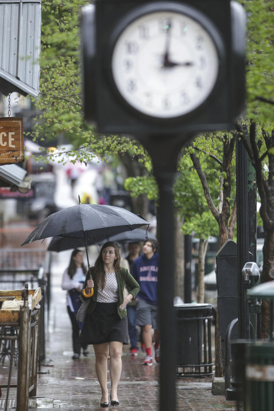 Stephanie Wolfgang walks past shops in downtown Athens, Ga., in a lull of storms Wednesday, April 5, 2017. The National Weather Service has issued severe weather warnings for the Athens-Clarke County area. (John Roark/Athens Banner-Herald via AP)