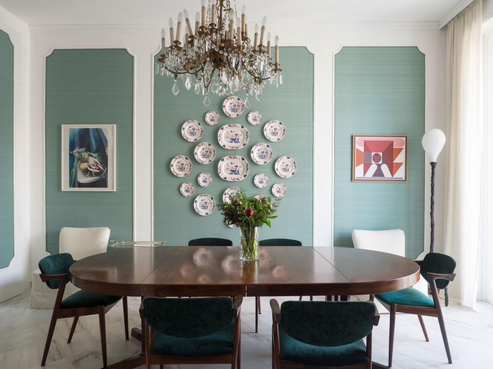The dining room displays family heirlooms including Meissen porcelain and a 1920s Italian chandelier; the table and chairs are vintage Kai Kristiansen.