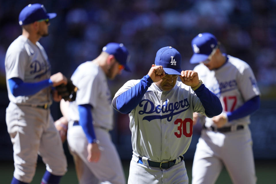 Los Angeles Dodgers manager Dave Roberts (30) walks off the field after replacing the pitcher leaving Dodgers shortstop Miguel Rojas, left, third baseman Max Muncy, second from left, and second baseman Miguel Vargas (17) on the mound during the fourth inning of a baseball game against the Arizona Diamondbacks Sunday, April 9, 2023, in Phoenix. (AP Photo/Ross D. Franklin)