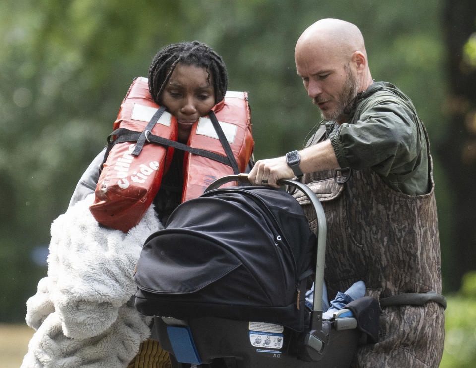 A woman is handed her child after being evacuated by boat from her homes with the help of deputies with the Montgomery County Sheriff's Office, Friday, May 3, 2024, in Conroe, Texas. Torrential rain is inundating southeastern Texas, forcing schools to cancel classes and closing numerous highways around Houston. (Jason Fochtman/Houston Chronicle via AP)