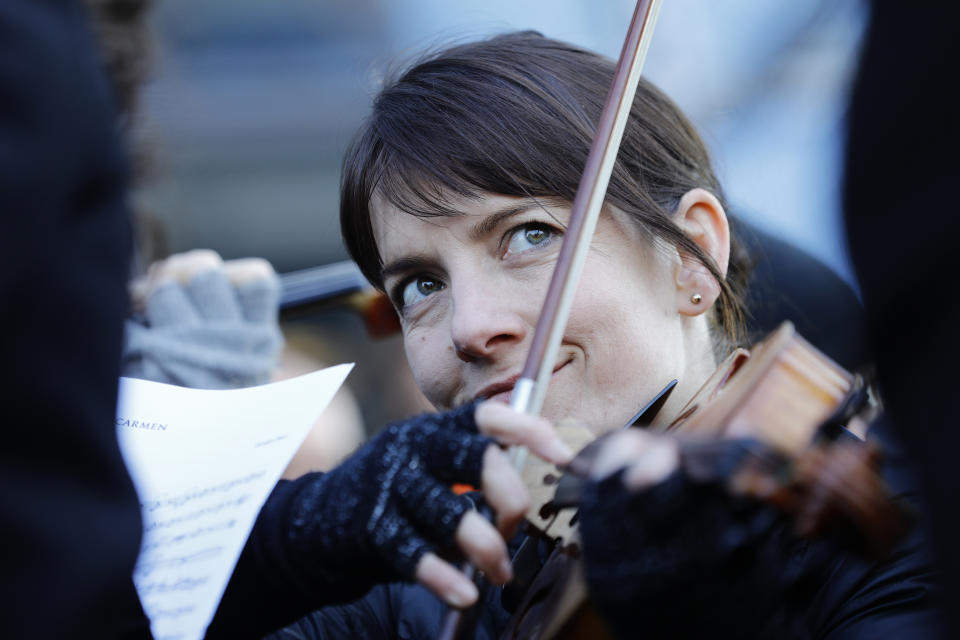 A striking musician of the Paris Opera house performs outside the Bastille Opera house Tuesday, Dec. 31, 2019 in Paris. (AP Photo/Kamil Zihnioglu)