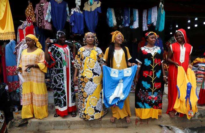 Women pose as models in front of a clothing store in a street of the popular district of Adjame in Abidjan, Ivory Coast, March 1, 2022.