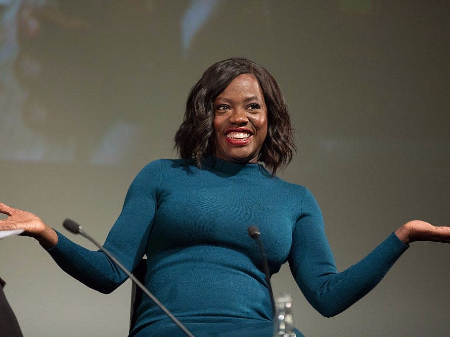 Viola Davis wears blue and holds her arms out at her sides at an event