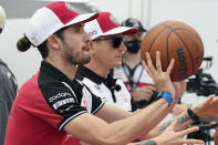 Alfa Romeo drivers Antonio Giovinazzi, of Italy, left, and Kimi Raikkonen, of Finland, right, shoot free throws at the Formula One U.S. Grand Prix auto race at the Circuit of the Americas, Thursday, Oct. 21, 2021, in Austin, Texas. F1 Teams took part in a free throw challenge as to help the NBA celebrate their 75th Anniversary. (AP Photo/Eric Gay)