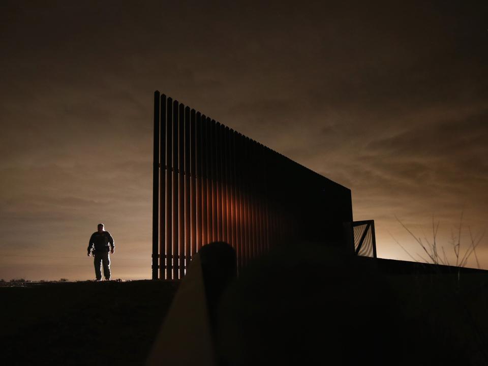 US Border Patrol agent Sal De Leon stands near a section of the US-Mexico border fence while stopping on patrol on in La Joya, Texas: Getty