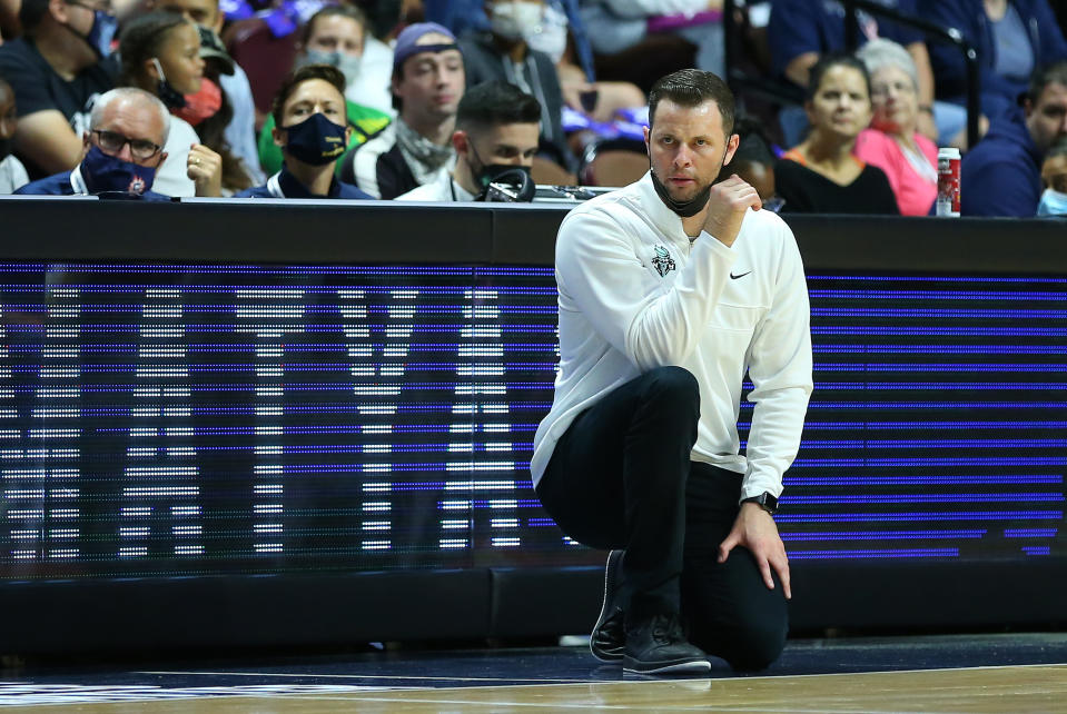 New York Liberty head coach Walt Hopkins kneels as he looks on from the sideline.