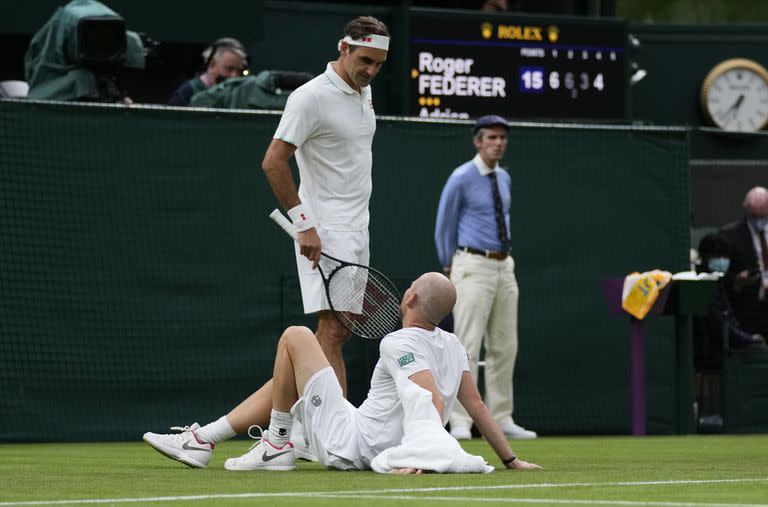 Momento de drama en Wimbledon 2021: Roger Federer hablando con Adrian Mannarino, tendido en el piso después de la lesión.

