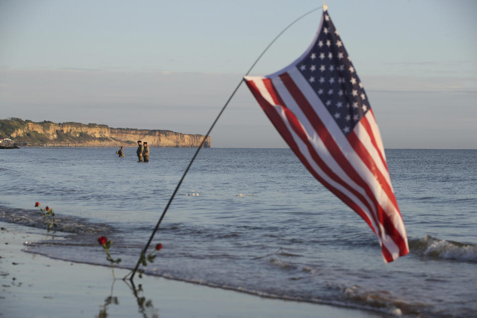 World War II reenactors stand in the sea on Omaha Beach in Saint-Laurent-sur-Mer, Normandy, Sunday, June 6, 2021, the day of 77th anniversary of the assault that helped bring an end to World War II. While France is planning to open up to vaccinated visitors starting next week, that comes too late for the D-Day anniversary. So for the second year in a row, most public commemoration events have been cancelled. (AP Photo/David Vincent)