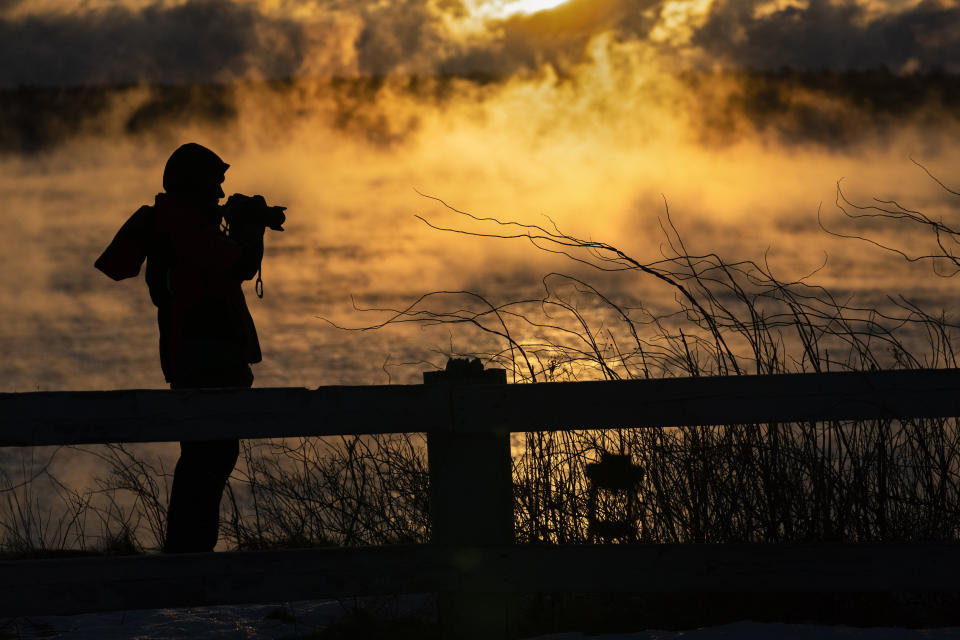 Kim Hunt of Cumberland, Maine, photographs arctic sea smoke on the coast of South Portland, Maine, Saturday, Feb. 4, 2023. The morning temperature was about -10 degrees Fahrenheit. (AP Photo/Robert F. Bukaty)