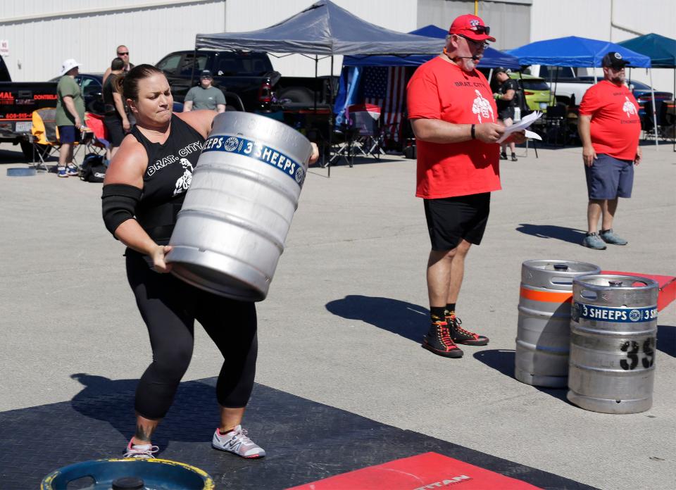 Deb McNally of Sun Prairie, Wis. lifts a full keg of beer during Brat City Strongmen competition held at 3 Sheeps Brewing, Saturday, July 30, 2022, in Sheboygan, Wis. The event raised funds for MDA  in coordination with the Sheboygan Professional Firefighters. Standing nearby is co-owner of Rage Fitness Todd Arnoldi.