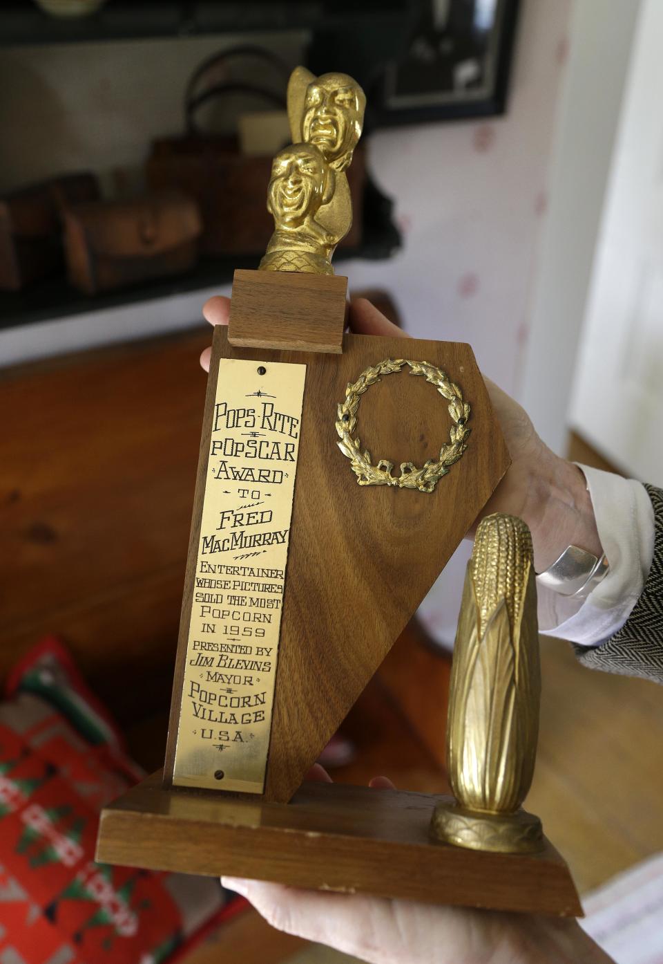 In this photo taken March 15, 2013 Kate MacMurray holds her father Fred MacMurray's favorite award at the MacMurray Ranch in Healdsburg, Calif. Oddly, MacMurray never was nominated for an Oscar or Emmy, but the good-natured actor told his daughter that if she wanted to put an award out to make it the one he got from an outfit called Popcorn Village USA commending him for making pictures that sold the most popcorn. “He adored popcorn,” MacMurray says with a laugh. (AP Photo/Eric Risberg)