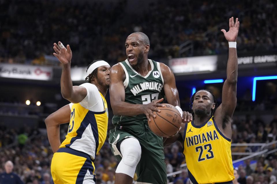 Milwaukee Bucks' Khris Middleton (22) makes a pass against Indiana Pacers' Myles Turner (33) and Aaron Nesmith (23) during the first half of Game 4 of the first round NBA playoff basketball series, Sunday, April 28, 2024, in Indianapolis. (AP Photo/Michael Conroy)