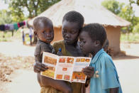 Children read a pamphlet about the dangers of landmines, in Moli village, Eastern Equatoria state, in South Sudan Friday, May 12, 2023. As South Sudanese trickle back into the country after a peace deal was signed in 2018 to end a five-year civil war, many are returning to areas riddled with mines left from decades of conflict. (AP Photo/Sam Mednick)